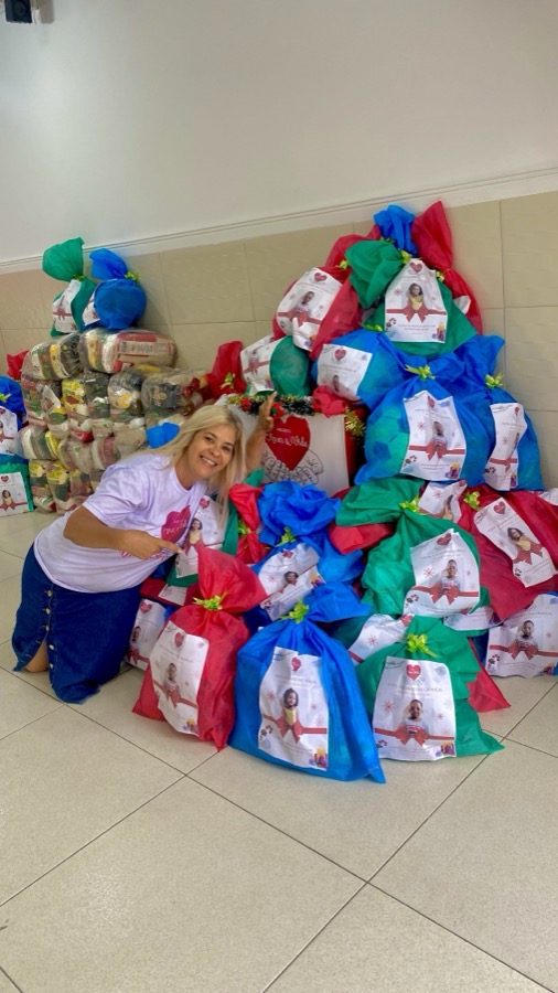 Voluntária ao lado de dezenas de sacolas de presente prontas para entrega